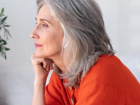 Mulher de cabelos grisalhos, em perfil, com expressão serena